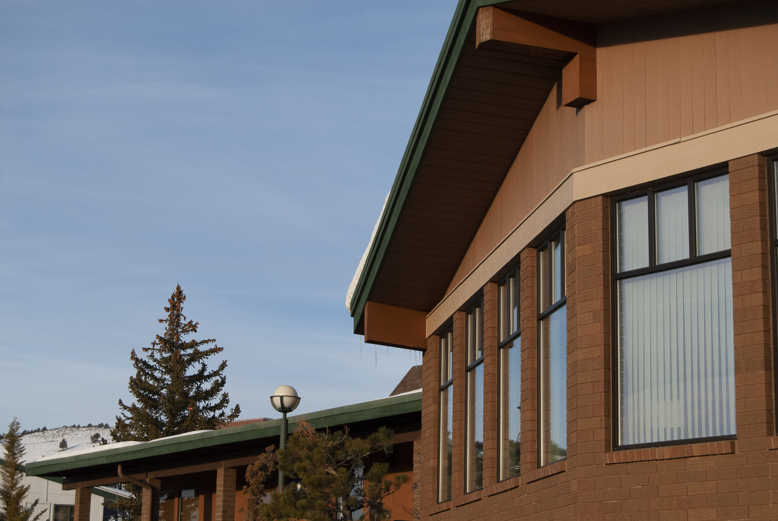 Exterior image of the cancer treatment center, taken at an angle. The sky is blue and cloudless. There is snow on the hills in the background. Patients of the CTC receive cancer treatment at this building.