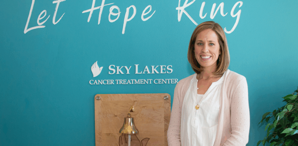 Nurse Hannah Sonerholm standing in front of a blue wall that says 