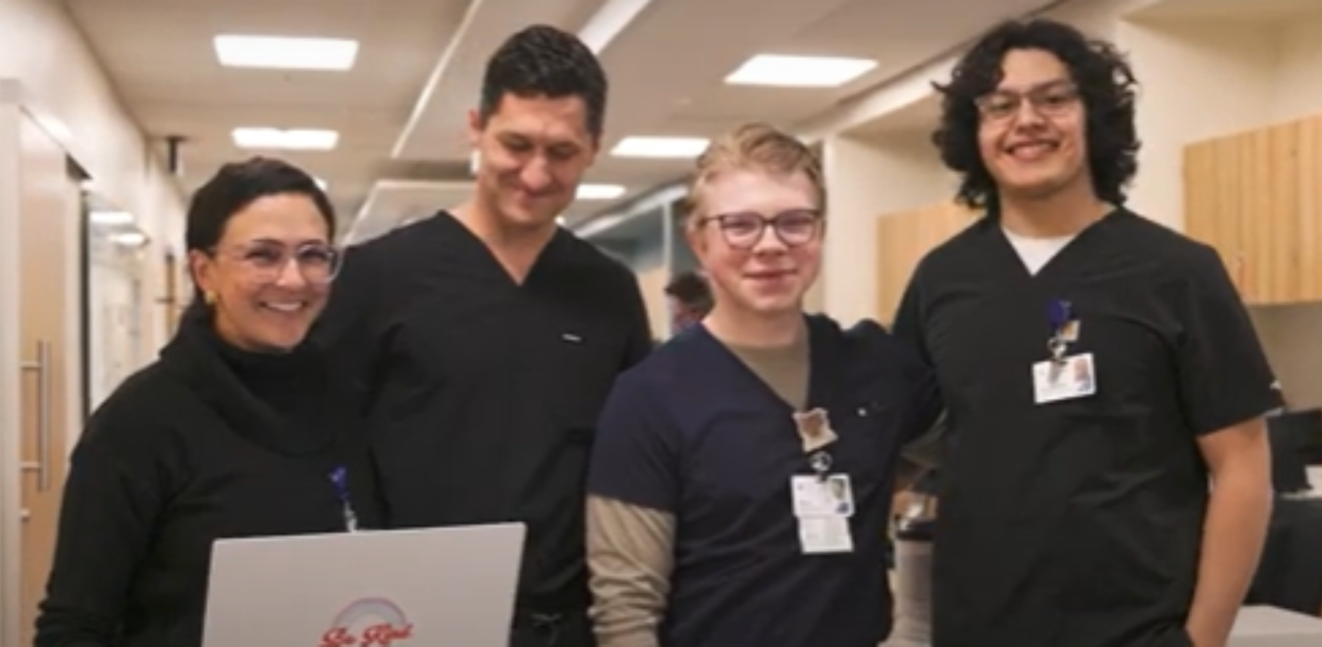 Four Sky Lakes employees in dark scrubs smile for the camera.