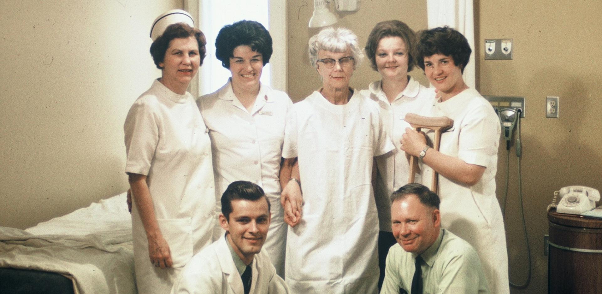 An old photo of nurses in Uniforms standing behind two male doctors. May have been taken in the 1960s or 1970s, when Sky Lakes was the Presbyterian Intercommunity Hospital.