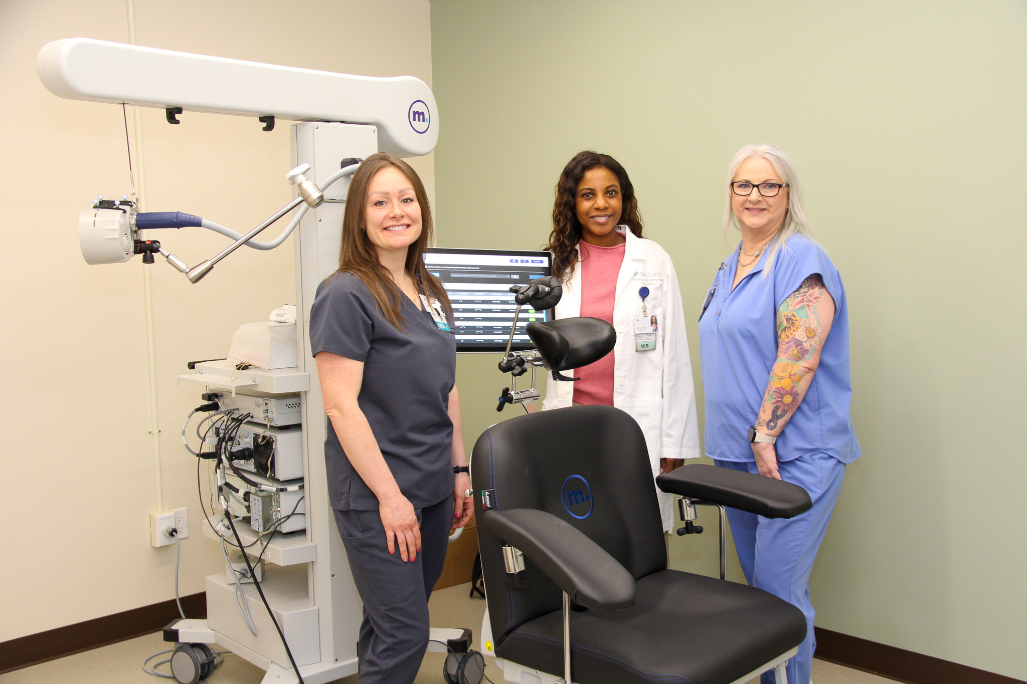 Three clinical employees standing around a Transcranial magnetic stimulation (TMS) machine